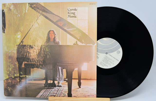 Vinyl record with cover featuring a person at a piano, on a light blue background