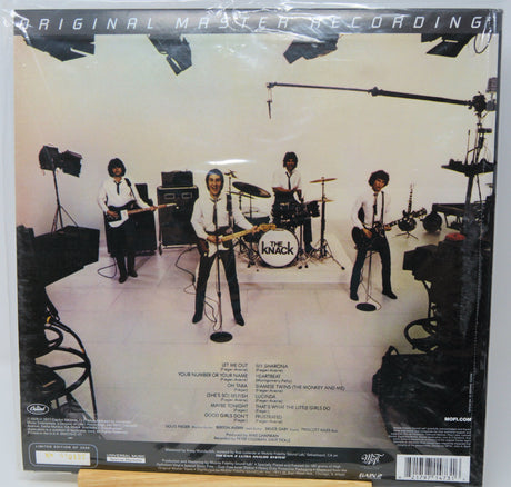 The back cover of a Knockout vinyl record sleeve, showing the original master recording studio scene with the band members performing. The cover features a white background with a black border, track listings, and a barcode at the bottom.