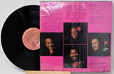 Vinyl record with a pink cover featuring black and white portraits and text.