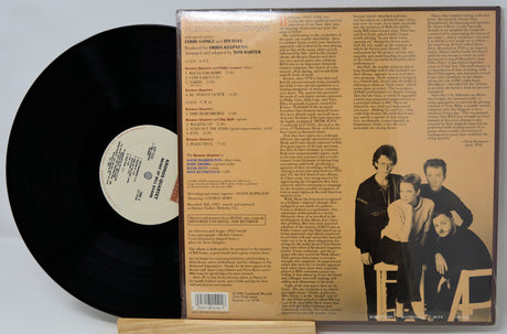 Vinyl record with its cover showing text and a photo of four people.