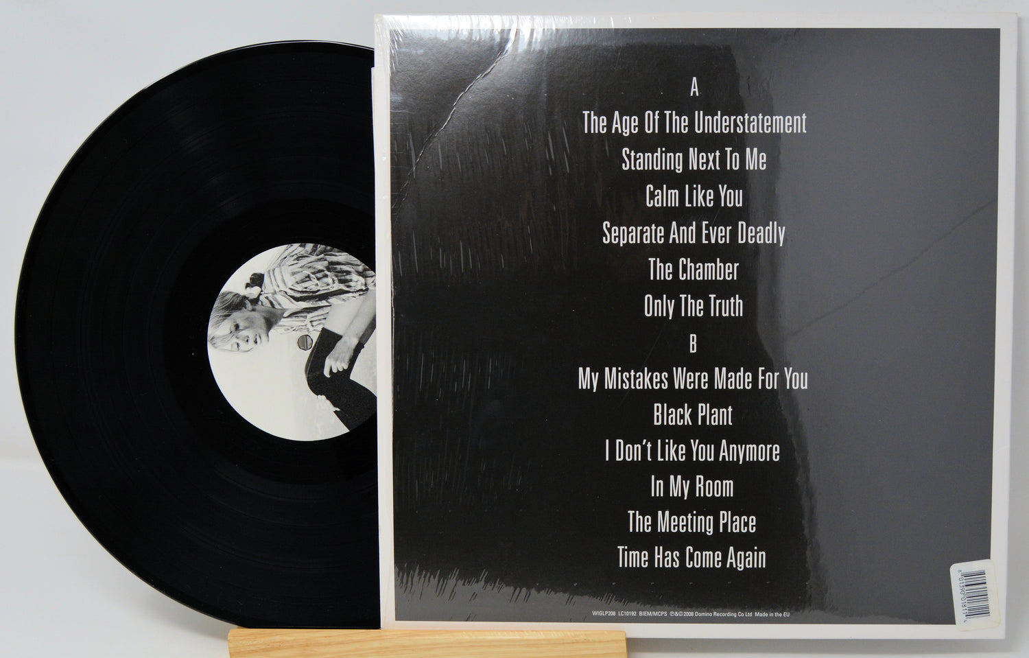 Vinyl record with cover displaying album tracklist on a light gray background