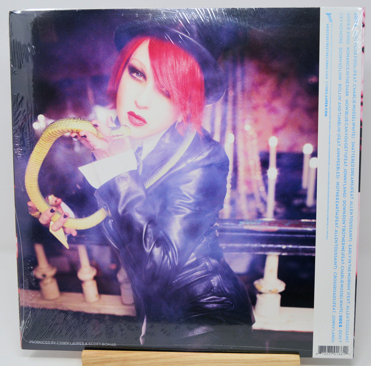 Vinyl record cover with a person in a dark outfit and hat holding an umbrella, surrounded by candles.