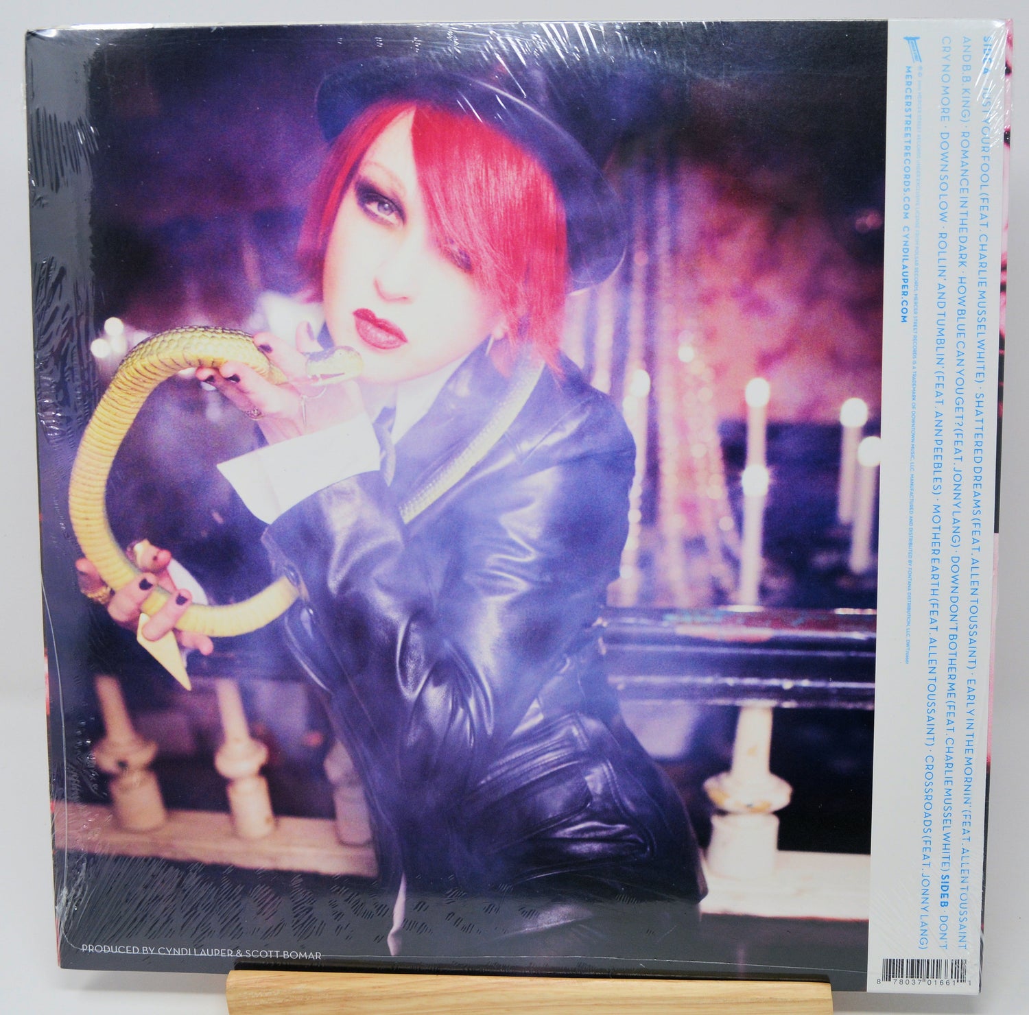 Vinyl record cover with a person in a dark outfit and hat holding an umbrella, surrounded by candles.