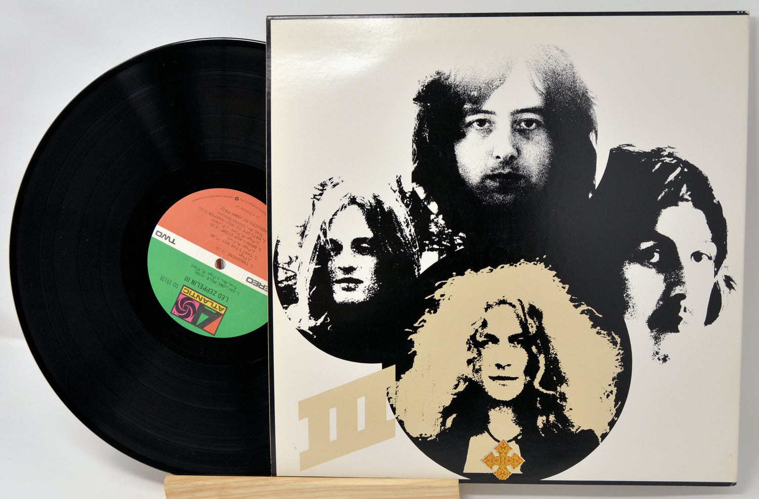 Vinyl record with a cover featuring black and white portraits of band members on a white background.