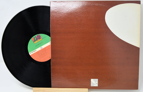 Vinyl record with a brown cover featuring a white circle design on a gray background