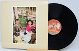 Vinyl record with a cover featuring a couple and a dog, on a light gray background.