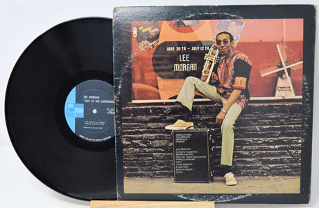 Vinyl record with cover featuring a musician on a bench, on a white background