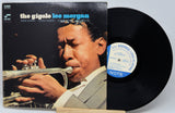 Vinyl record with cover featuring a musician playing a trumpet, on a light gray background.