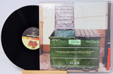 Vinyl record with a cover showing a dumpster and a white wall.