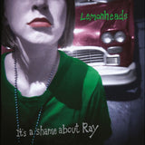 Album cover art for Lemonheads' 'It's a shame about Ray', featuring a close-up of a woman in a green top with a red vintage car in the background.
