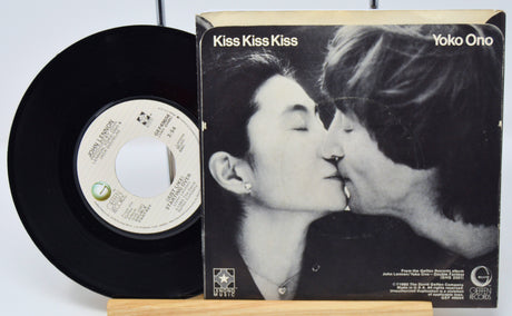 Vinyl record and cover with a black and white image of two people kissing, titled 'Kiss Kiss Kiss' by Yoko Ono.
