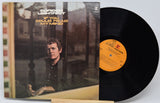 Vinyl record with cover featuring a person's portrait and album title.