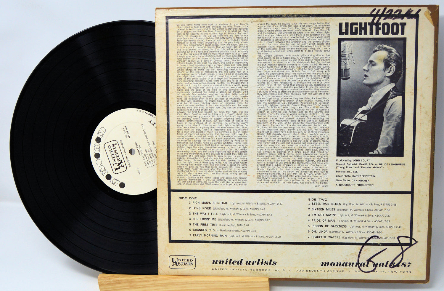 Vinyl record with a cover featuring text and a black and white photo of a person, on a light blue background.