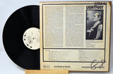 Vinyl record with a cover featuring text and a black and white photo of a person, on a light blue background.