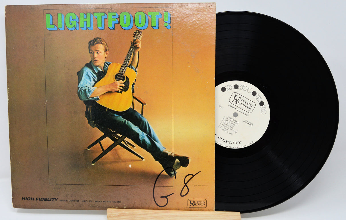 Vinyl record with cover featuring a person playing guitar, on a white background