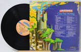 A vinyl record partially pulled from its album jacket, showing the black record on the left and the colorful back cover on the right. The cover features the title 'Lighthouse One Fine Morning' with a whimsical illustrated tower and landscape on a purple background.