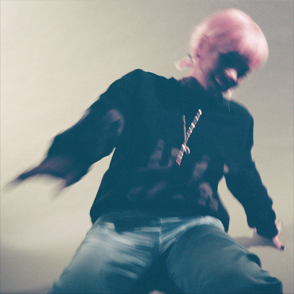 Vinyl record cover showing Lily Allen  with pink hair wearing a dark hoodie with a logo, sitting against a plain background