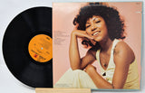 Vinyl record and cover featuring a woman on a light pink background