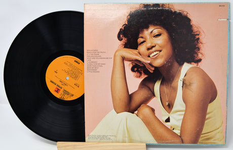 Vinyl record and cover featuring a woman on a light pink background