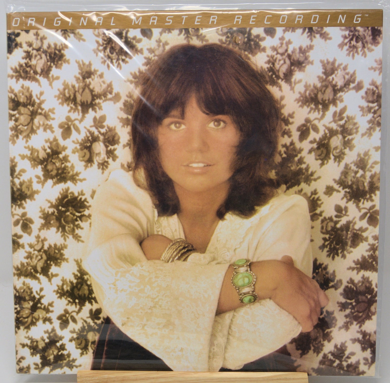 Vinyl record sleeve for 'Original Master Recording' featuring a portrait of a woman with brown hair against a floral background, photographed in its plastic shrink wrap.