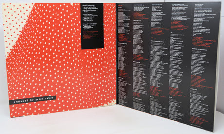 An open printed booklet or album-style cover spread on a white surface, showing a red-orange and white polka-dot patterned left page and a black right page filled with small white and orange text.