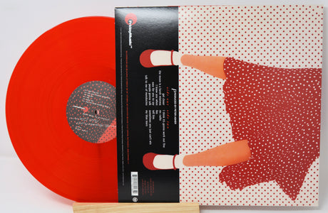 A vinyl record partially pulled from its illustrated album cover, showing a translucent bright red record and matching cover art with a stylized figure in a red polka-dot dress on a white background.