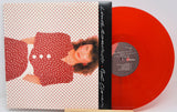 Vinyl record album with a red-and-white polka dot cover showing a woman in a red polka dot dress, partially pulled from a translucent bright red vinyl record on a stand.