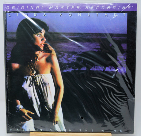 Linda Ronstadt 'Hasn't Darn the Wind' original master recording vinyl LP album cover, sealed in plastic shrink wrap, displayed on a wooden stand.