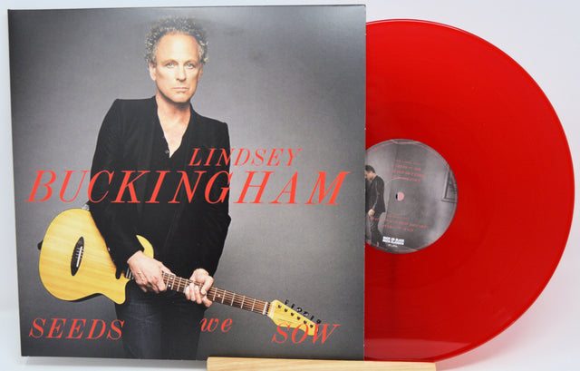 Lindsey Buckingham's 'Seeds We Sow' 12-inch vinyl record shown with its album cover and a translucent red vinyl disc on a white background.