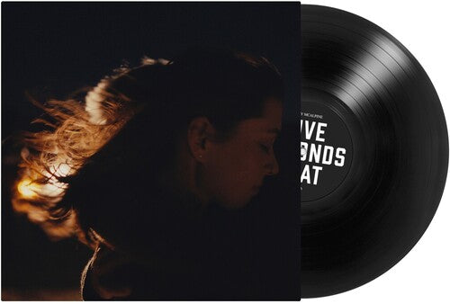 Vinyl record with a person's face on one side and text on the other, set against a dark background.