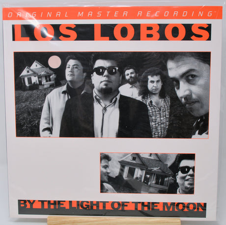 Los Lobos 'By the Light of the Moon' vinyl record cover, showing the band members in black and white portraits with orange text on a white background.