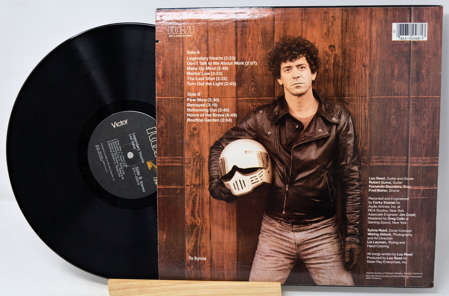 Vinyl record with a cover featuring a person holding a helmet, on a light gray background