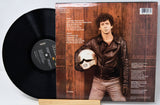 Vinyl record with a cover featuring a person holding a helmet, on a light gray background
