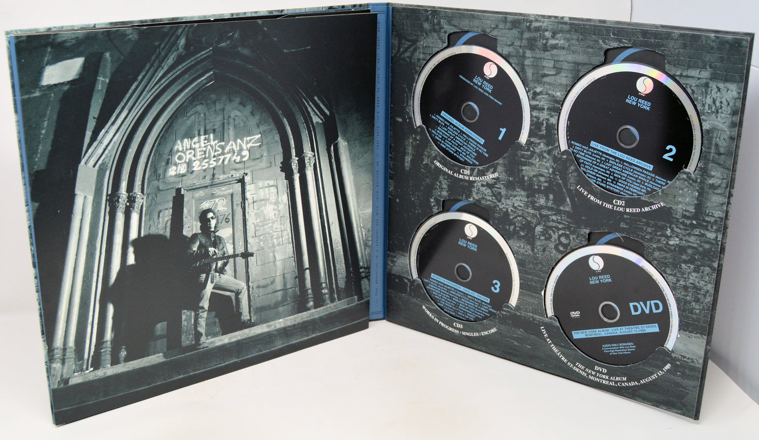 Open DVD case with four discs and a cover featuring a silhouette of a person playing guitar.