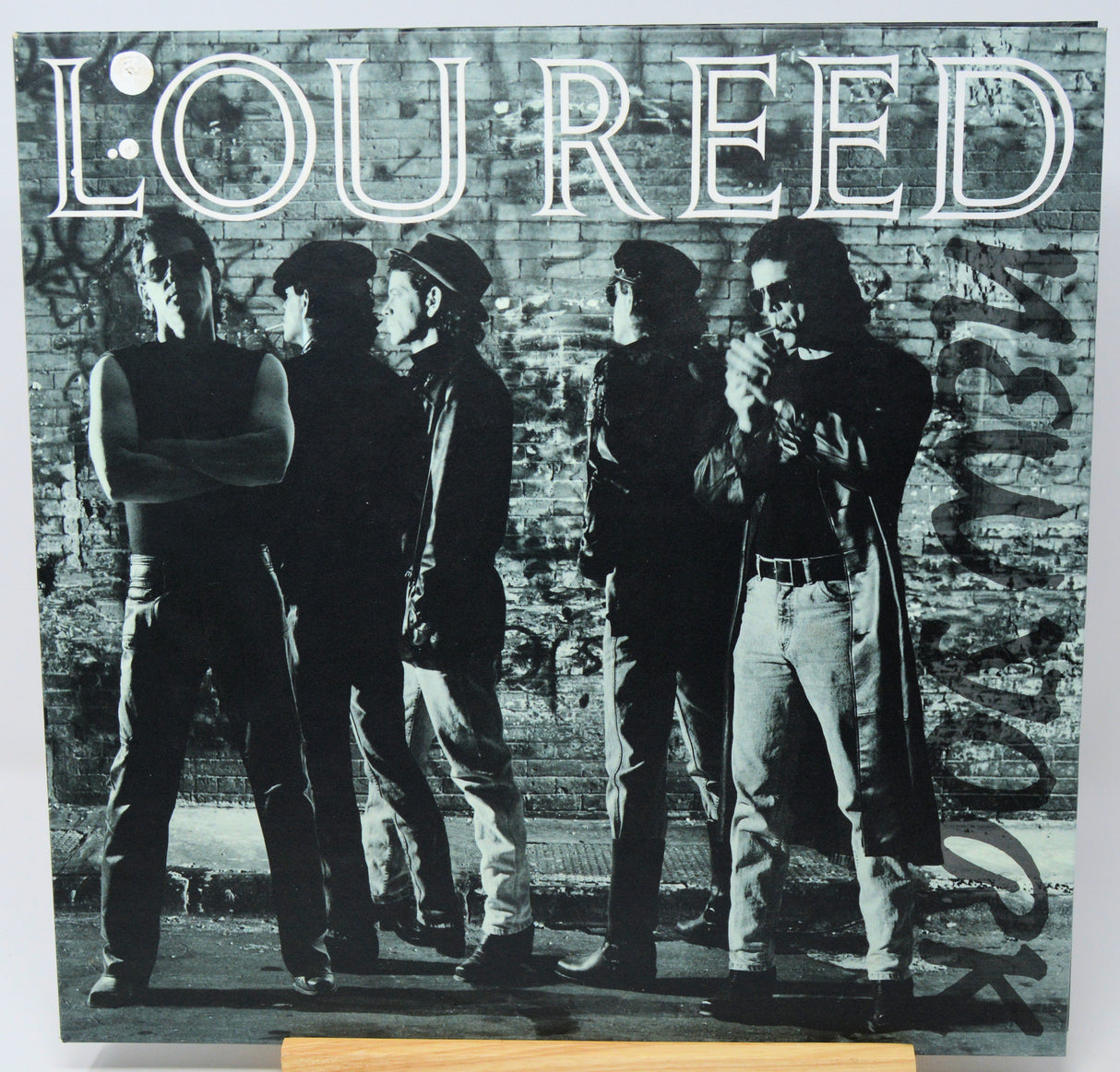 Album cover with a black and white photo of a group of people against a brick wall, featuring the name 'Lou Reed'.