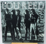 Album cover with a black and white photo of a group of people against a brick wall, featuring the name 'Lou Reed'.