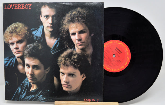 A vinyl record and its cover featuring members of the band Loverboy with the album title 'Keep It Up' displayed.