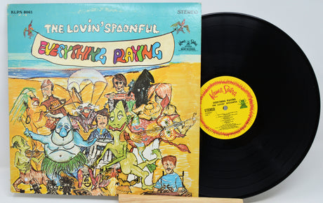 Vinyl record album 'Everything Playing' by The Lovin' Spoonful, showing the illustrated front cover and the black LP with a yellow label partially pulled out, photographed on a light gray background.
