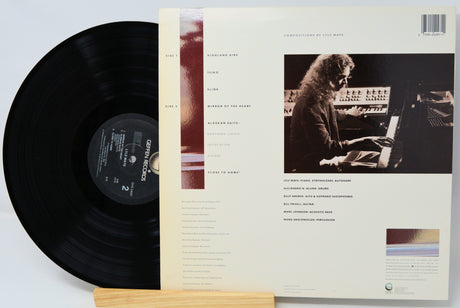 Vinyl record with its cover featuring a person at a keyboard on a light gray background