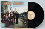 Vinyl record with cover featuring a group of people on a sidewalk.