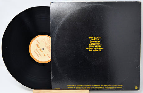 Vinyl record with a black cover featuring yellow text on a white background