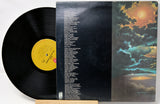 Vinyl record with a colorful album cover featuring a sunset over water.
