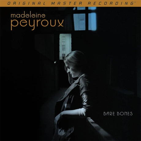 Album cover for Madeleine Peyroux's 'Bare Bones' featuring a dark, moody photograph of a woman in profile in a dim interior, with the artist's name and album title in white and gold text.