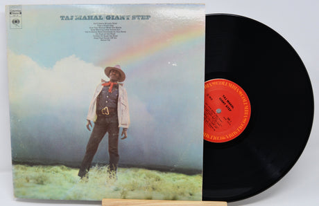Vinyl record with cover featuring a person in a hat and overalls against a rainbow sky.