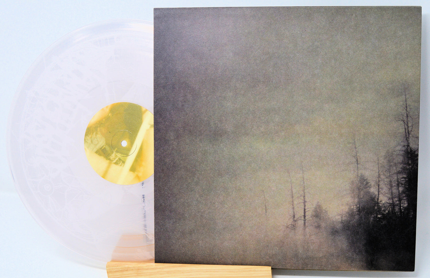 Abstract art piece with a forest scene on a gray background, featuring a gold circular object.