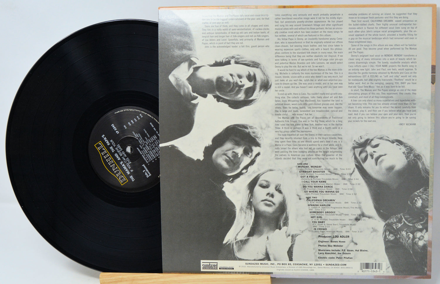 A vinyl record partially pulled from its open back cover, showing the black record on the left and printed liner art and tracklist text on the right. The center label reads Dunhill Records.