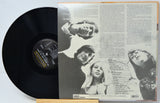 A vinyl record partially pulled from its open back cover, showing the black record on the left and printed liner art and tracklist text on the right. The center label reads Dunhill Records.
