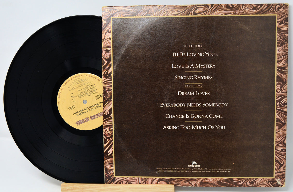 Vinyl record with marbled cover and tracklist on a light gray background