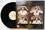 Vinyl record with a black cover featuring a collage of images and text.