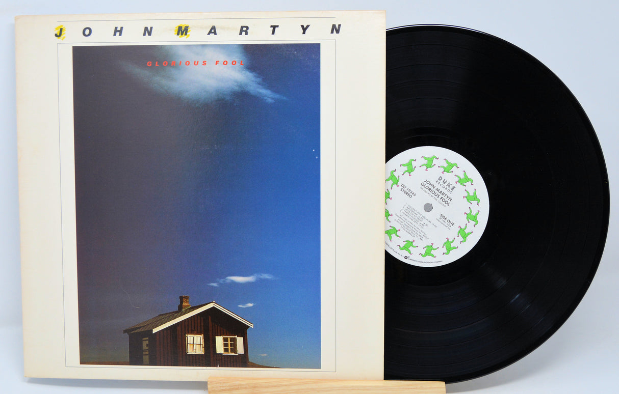 Vinyl record titled Glorious Fool by John Martyn showing the album and front cover with a picture of a house on it.